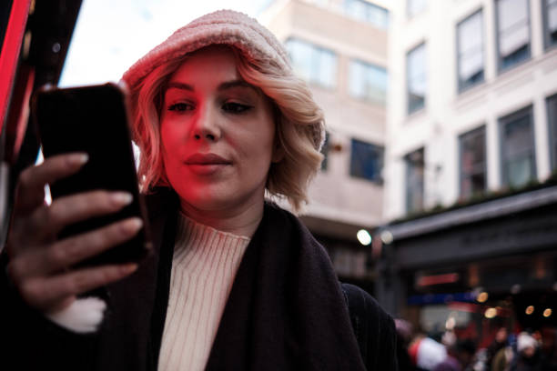 istock Young woman using phone standing beside red neon. 1463867107