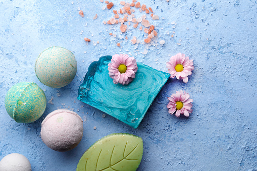 Homemade soaps and bath bombs with flower on blue background