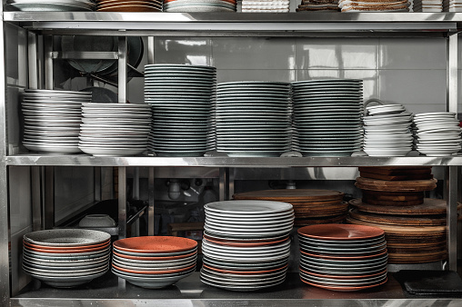 Clean dishes in the restaurant on the shelves. Multicolored plates in the kitchen of the cafe. Many stacks of plates