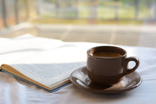 istock Aromatic morning coffee and open book on bed indoors 1463870986