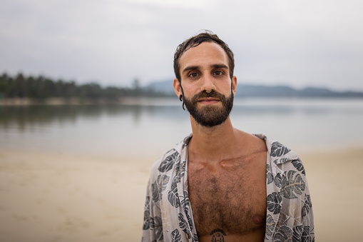 Portrait of a handsome man standing on the beach by the sea in Thailand.
