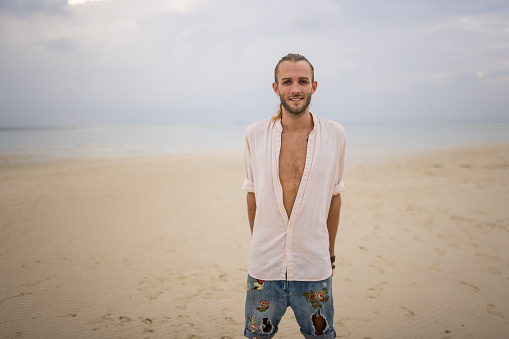 Portrait of a handsome man standing on the beach by the sea in Thailand.