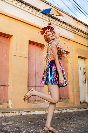 Portrait of a Brazilian woman during a carnival block. Woman playing with confetti and Frevo umbrella.