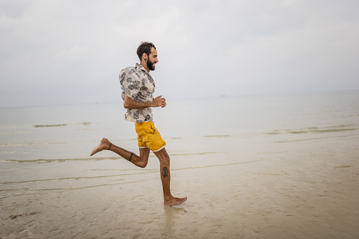 Portrait of a handsome man running on the beach by the sea in Thailand.