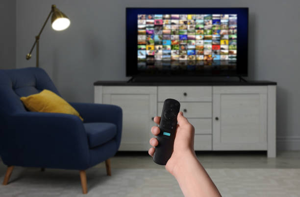 istock Woman with remote control changing channels while watching TV at home, closeup 1463873195