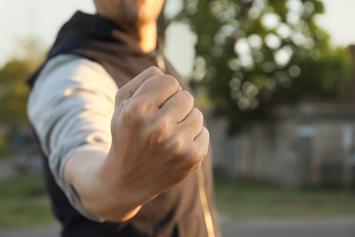 Angry man with clenched fist outdoors, closeup