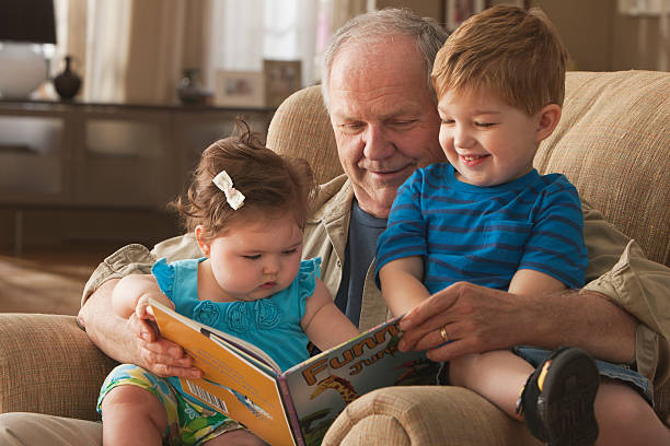 nonno lettura libro per nipoti - sibling baby three people baby girls foto e immagini stock