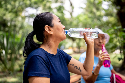 Mature woman drinking water on the public park