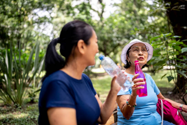 istock Mother and daughter talking while drink water on the public park 1463873525