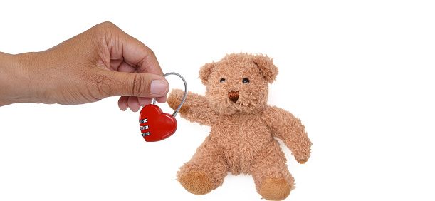 Hand holding heart lock next to teddy bear