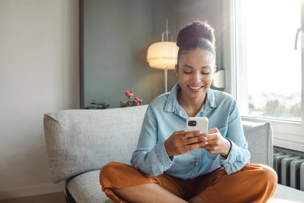 A young beautiful woman using a smart phone at home stock photo