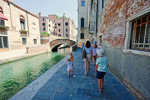 Mother with kids walking near canal in Venice, Italy.