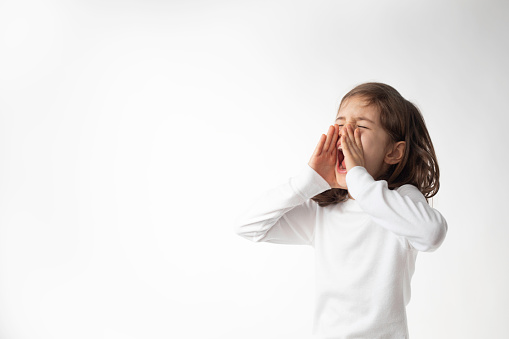 A little girl is screaming, white background.