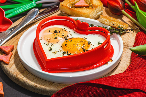 Pair of fried eggs in the shape of hearts on two pieces of toast on a plate