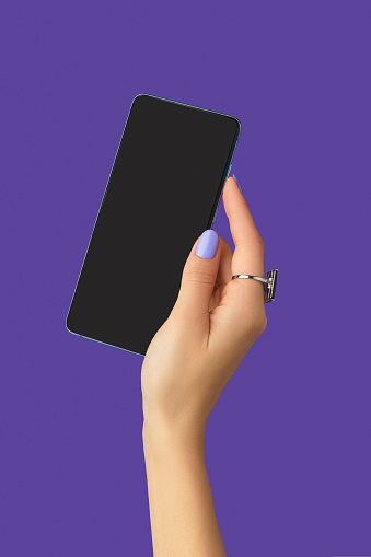 Manicured womans hands holding smartphone with blank screen. Work from home office education concept.
