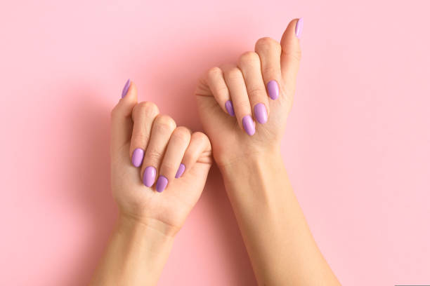 istock Womans hands with fashionable lavender manicure on pink background. Spring summer nail design 1463881237