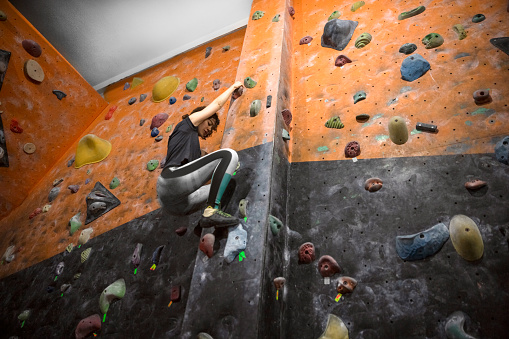 Young adult woman climbing on climbing wall