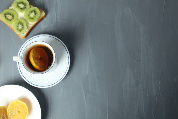 breakfast with sandwiches tea with lemon sandwich with kiwi fruit on a gray background with space for copyspace text. Healthy food breakfast snack tea break.