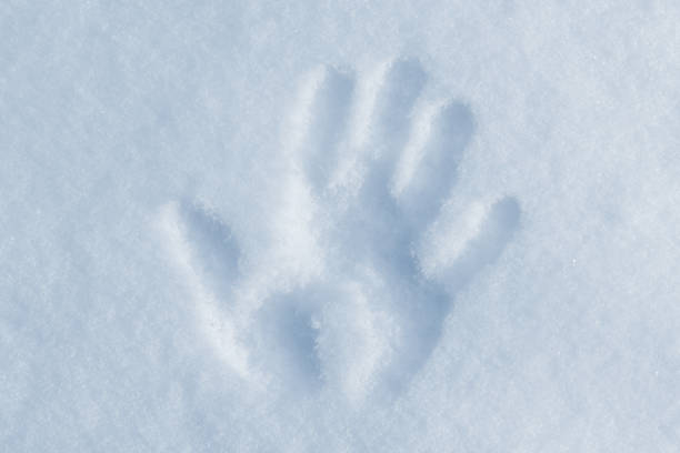 Child wearing winter gloves holding icy snow heart in hands