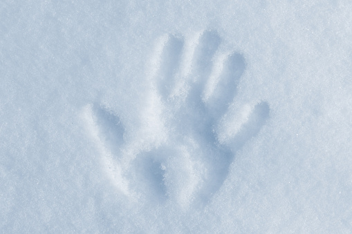Palm print on a snowdrift on a sunny winter day, close-up photo, top view
