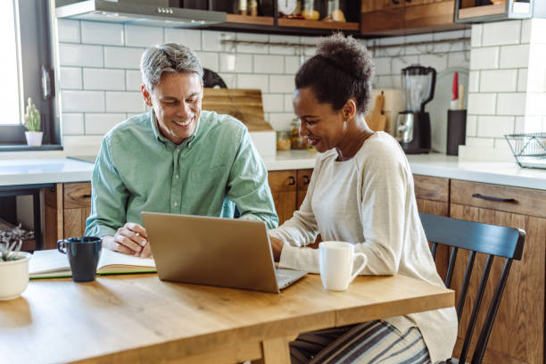 istock Multi-racial mature couple using laptop at home 1463887634