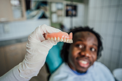 An orthodontist conducts a consultation about dental prosthetics with a male patient