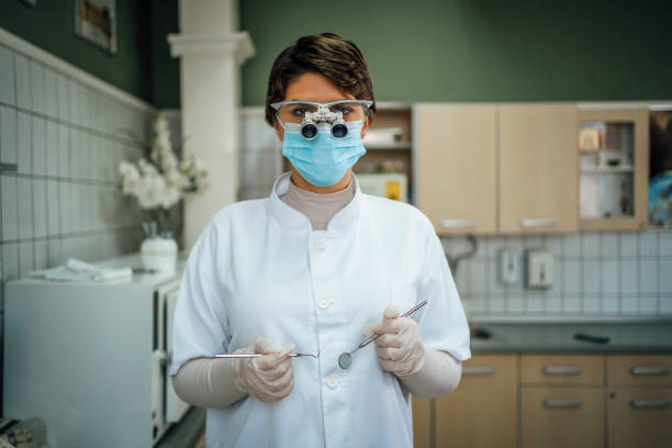 Young female dentist with microscope glasses and dental equipment tools in dental office