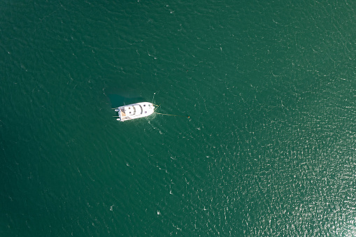 Small fishing white boat aerial above top view on green turquoise sea water