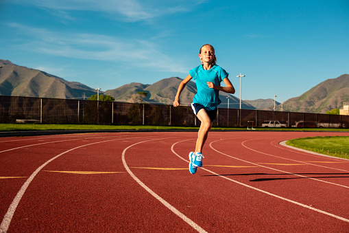 A young child practices running on a public track. Image taken in Utah, USA.