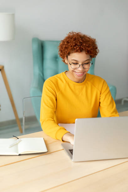 istock African american girl using laptop at home office looking at screen typing chatting reading writing email. Young woman having virtual meeting online chat video call conference Work learning from home 1463894283