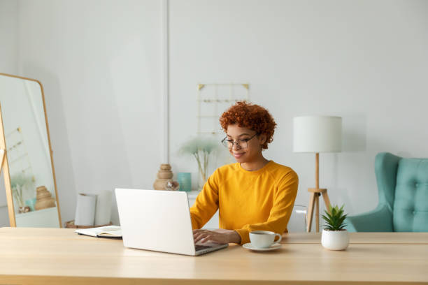 istock African american girl using laptop at home office looking at screen typing chatting reading writing email. Young woman having virtual meeting online chat video call conference Work learning from home 1463894285