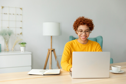 African american girl using laptop at home office looking at screen typing chatting reading writing email. Young woman having virtual meeting online chat video call conference. Work learning from home