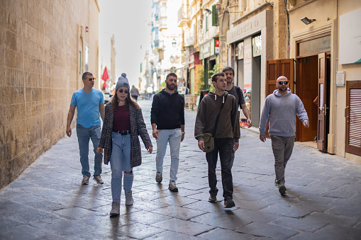 Young people, friends, are walking together through the city street of Valletta