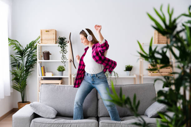 istock Young woman dancing on sofa while listening to music 1463896452