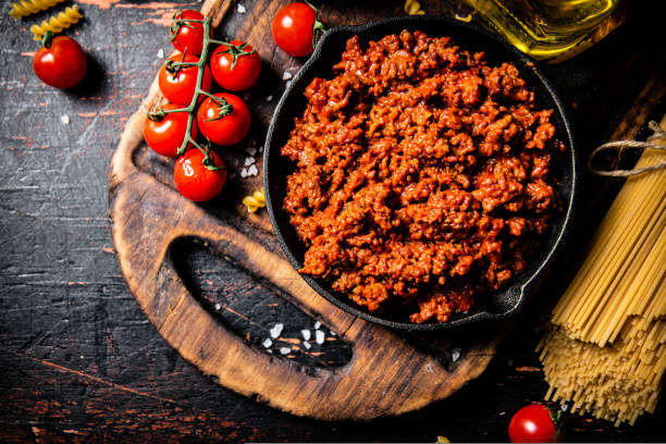istock Bolognese sauce on a cutting board with cherry tomatoes and dry pasta. 1463896699