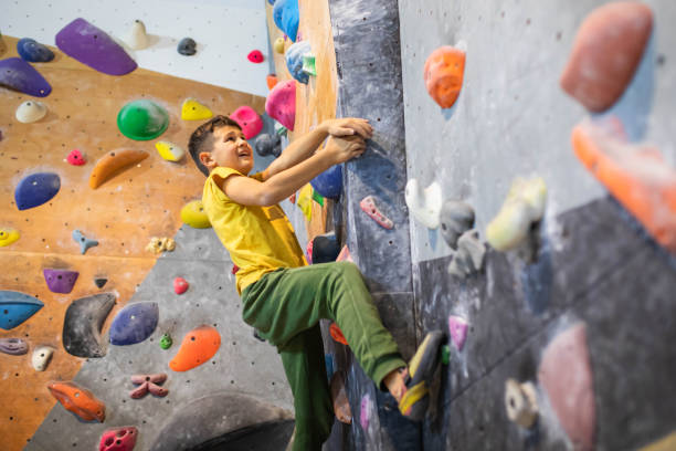 A boy climber climbing at the bouldering gym stock photo