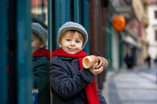 Child in the center of Prague, eating traditional czech dessert trdelnik in the city center