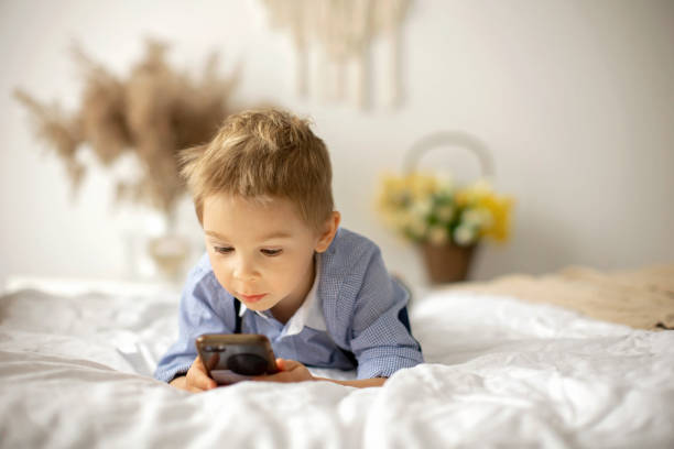 istock Blond preschool child, cute boy, playing on mobile phone in bed 1463898615