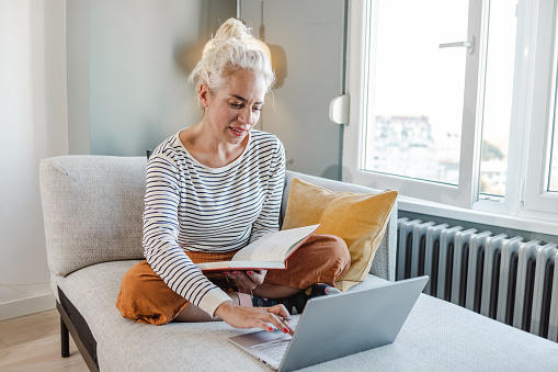 Beautiful blond hair woman working sitting on the sofa and attending online course