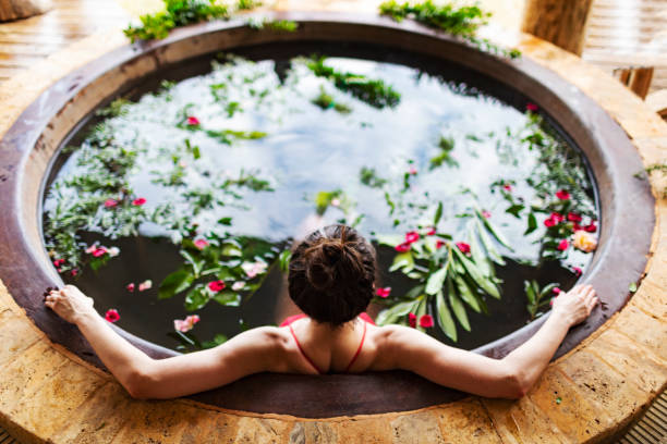 Giovane donna che si rilassa in hotel spa in vasca idromassaggio all'aperto - foto stock