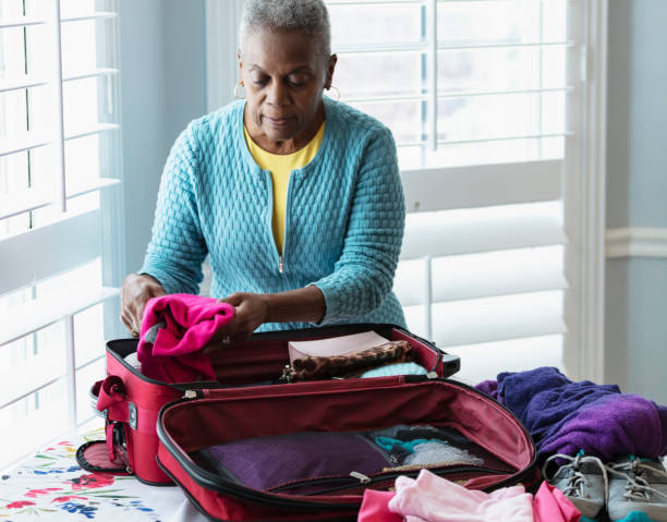 mulher afro-americana sênior que embala a mala na mesa - luggage packing suitcase old - fotografias e filmes do acervo