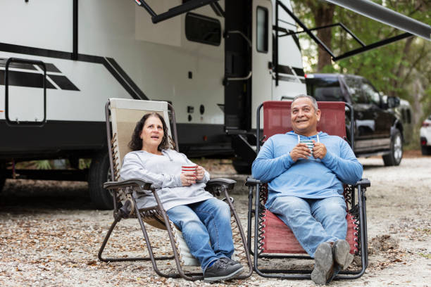 istock Multiracial couple sit by camper in RV park drinking coffee 1463906219