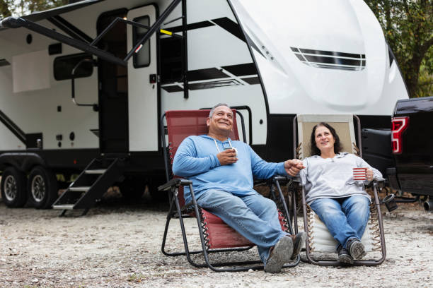 Multiracial couple sitting in chairs by camper in RV park