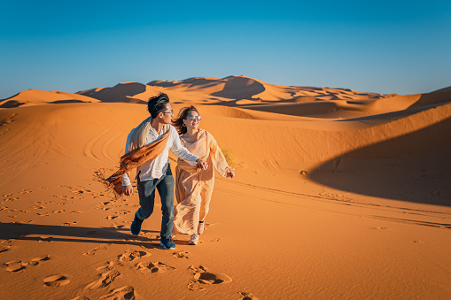 Portrait Asian Chinese Couple running in Morocco Sahara Desert