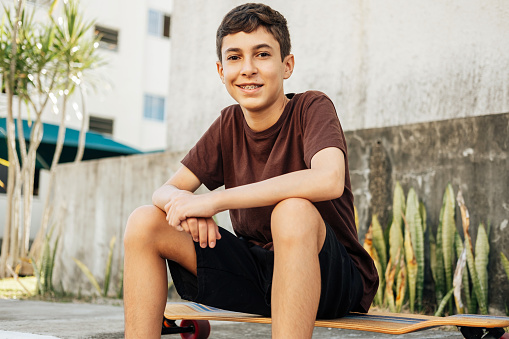 Portrait of teen boy sitting on skateboard