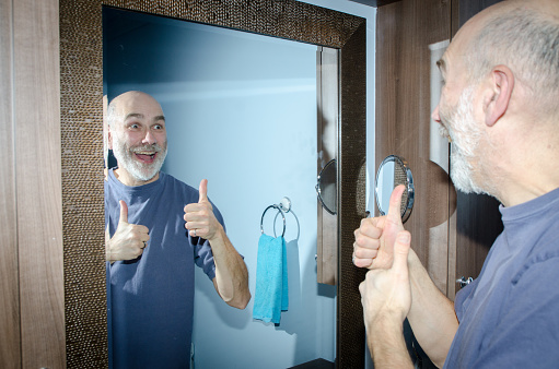 Happy mature man in front of mirror