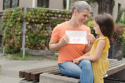 Portrait of a happy mother and her little daughter surprising her with a drawing