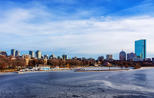 Boston skyline on a cold winter day as seen across an icy Charles River. The Charles River Esplanade along water's edge and Back Bay neighborhood are featured.