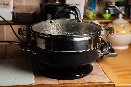 Saucepan electric steamer on the kitchen table. A metal modern device for steaming diet food.