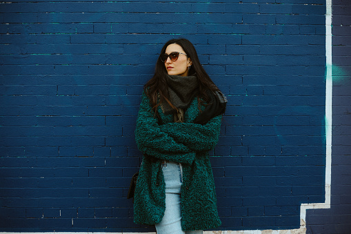 Portrait of a young woman against the vintage brick wall, wearing a fake fur coat, in Brooklyn, NYC